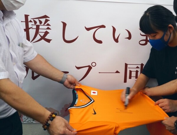決勝戦で使用した日の丸入りのユニフォームにサインをする岡本碧優選手